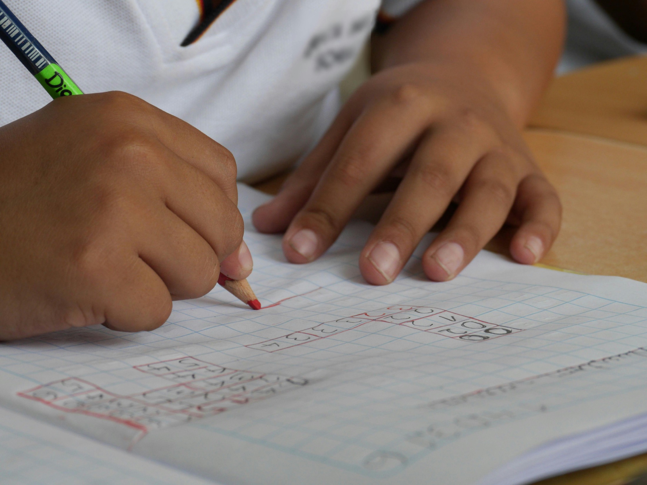 A learner working through maths in a graph-paper notebook